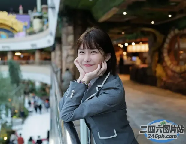 穿着灰色夹克的女人靠在商场的栏杆上