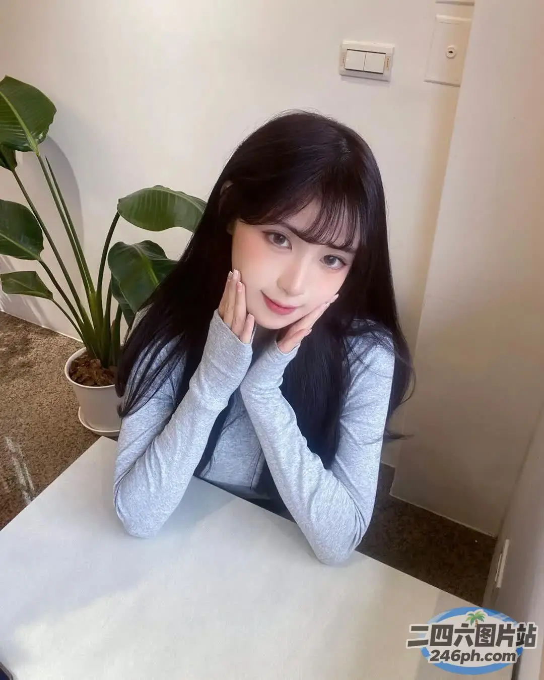 有一位女士拿着笔记本电脑坐在桌子旁