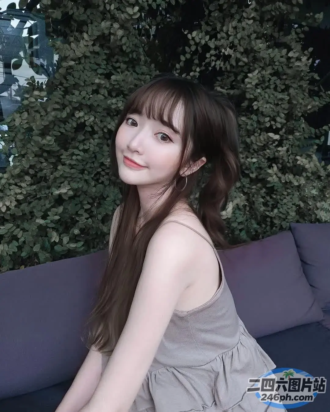 一个女人坐在灌木丛旁边的沙发上的特写