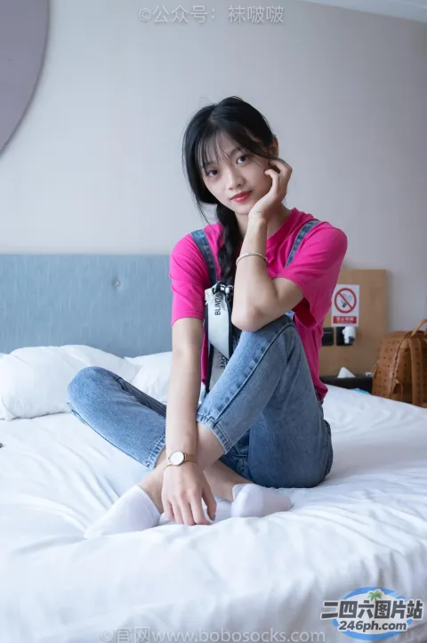 坐在床上的阿拉夫德女人，穿着粉红色的衬衫和牛仔裤