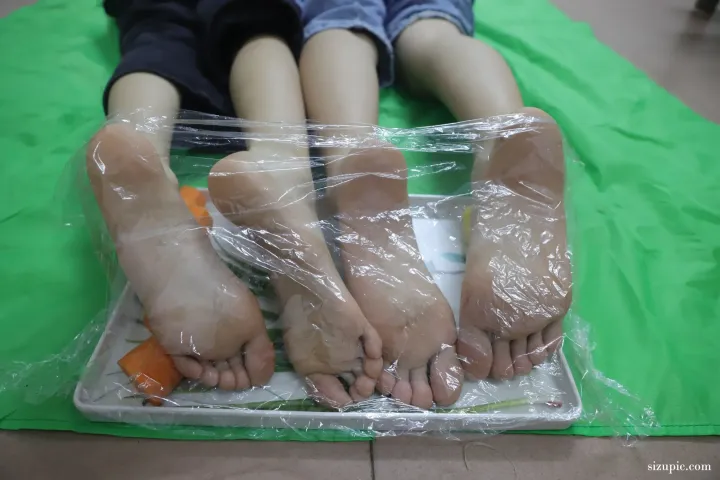 有两个人坐在铺有保鲜膜的垫子上