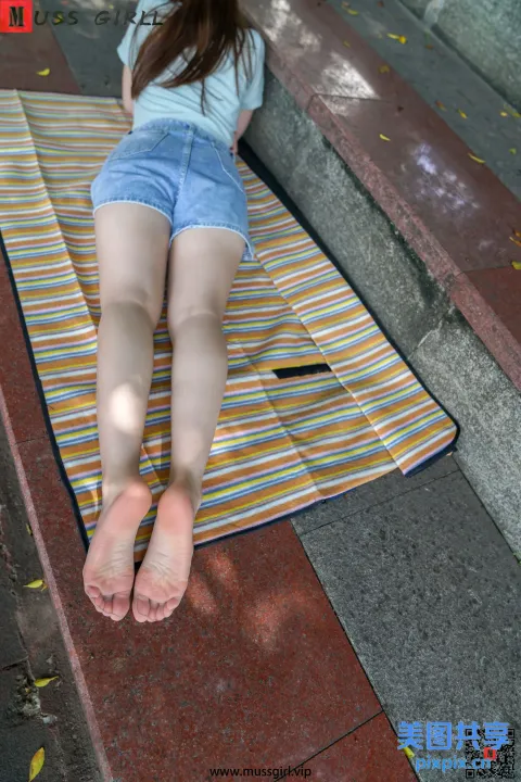 被拉夫的妇女躺在地上的毛巾上，双脚抬起