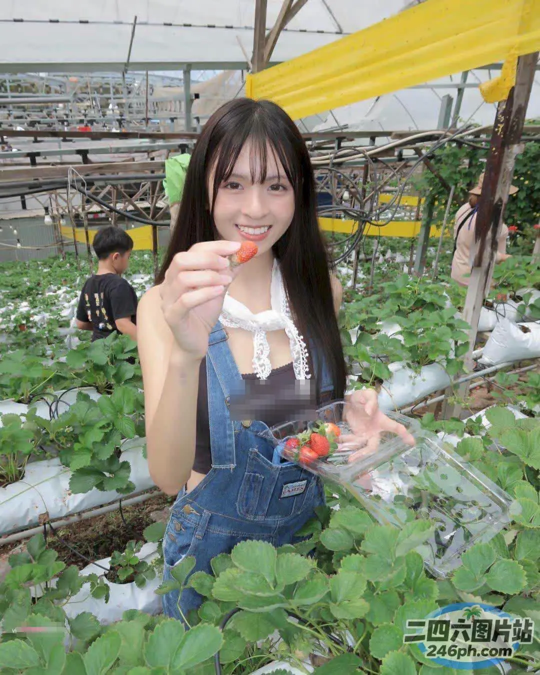 穿着工作服的 Araffe 女人在温室里拿着草莓