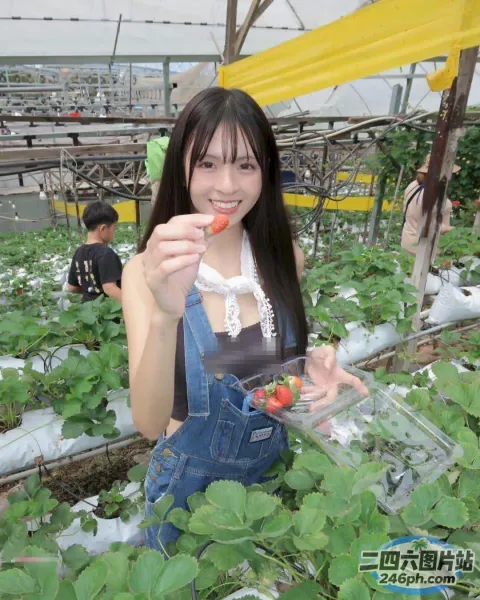 穿着工作服的 Araffe 女人在温室里拿着草莓