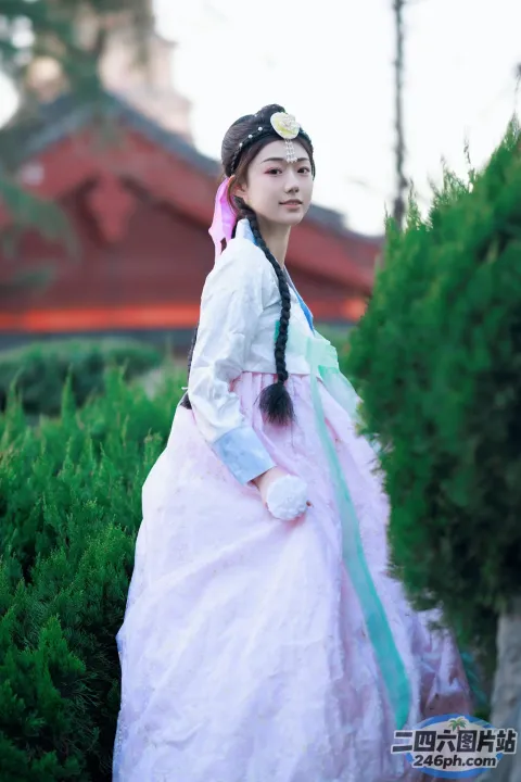 一个穿着粉红色连衣裙的女人站在灌木丛附近的特写