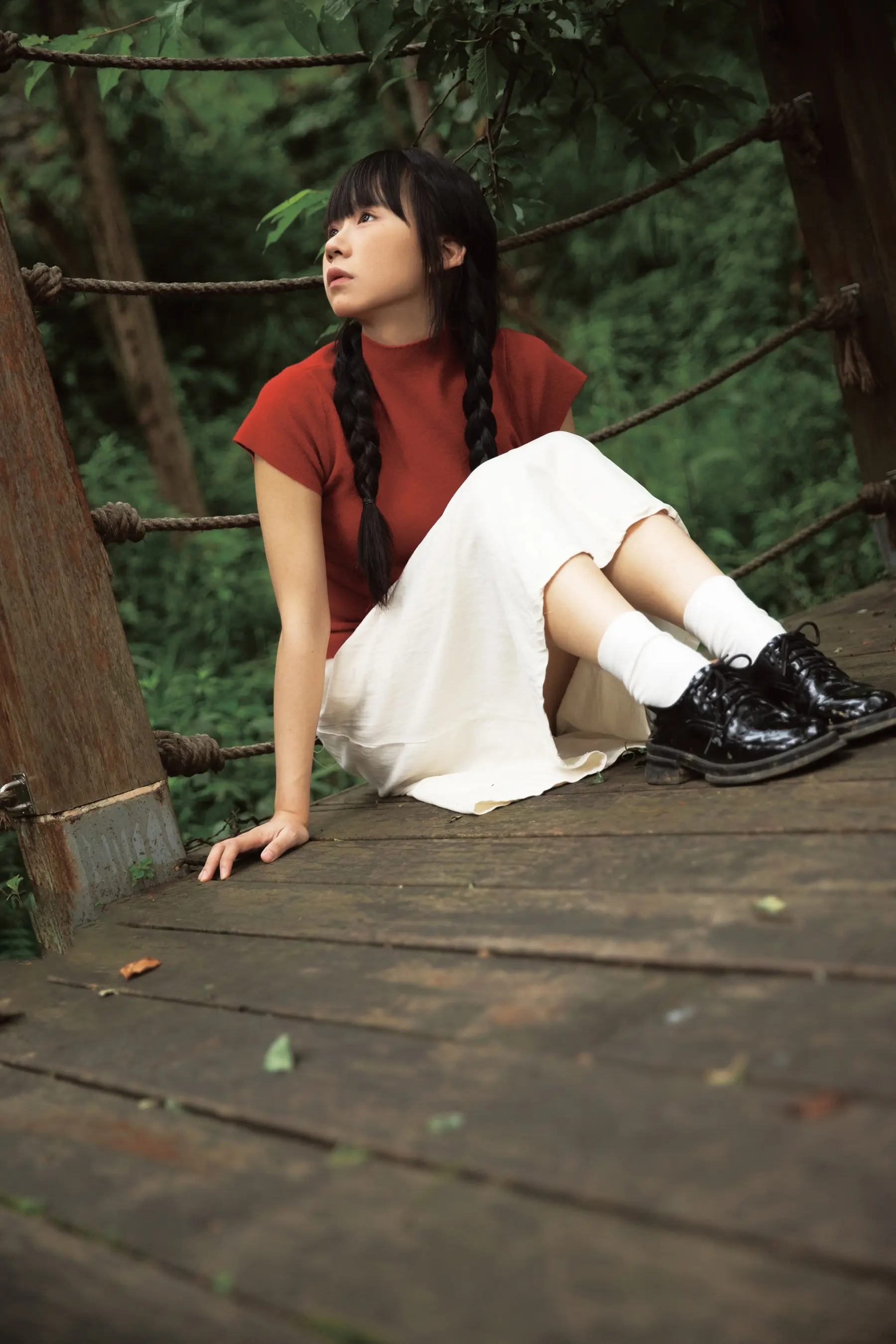 有一个女人坐在木桥上，双腿交叉