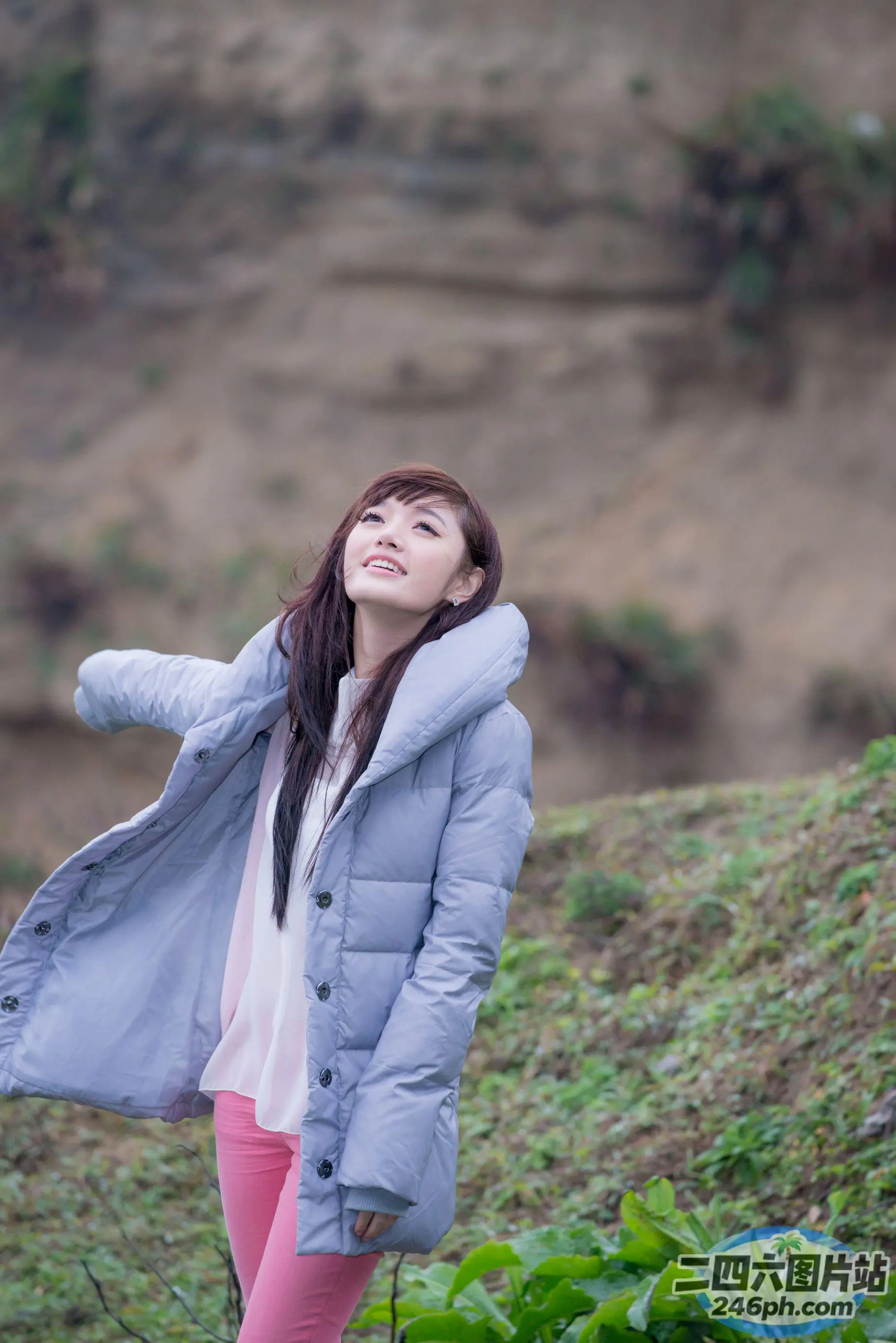 穿着蓝色夹克和粉红色裤子的 arafed 女人站在田野里