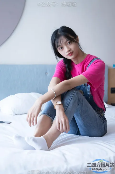 阿拉菲女人坐在床上，穿着粉红色衬衫和牛仔裤