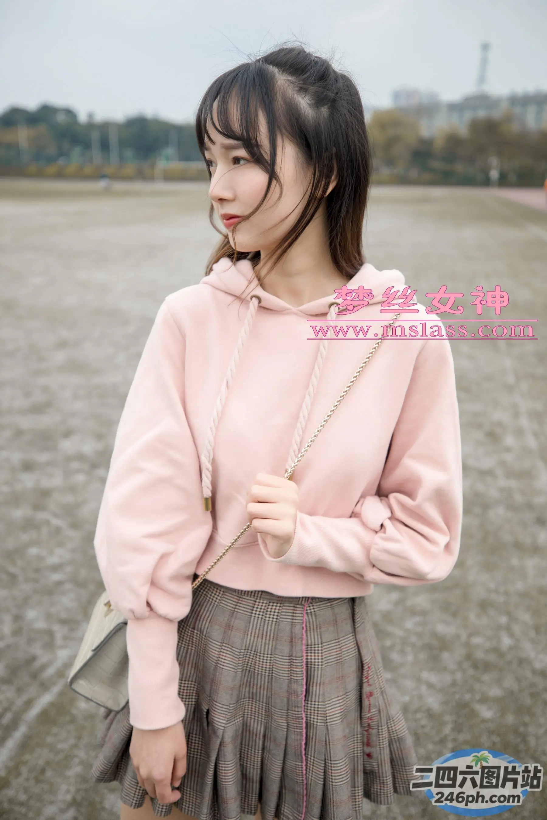 一个穿着粉红色运动衫和裙子的女人站在湖前