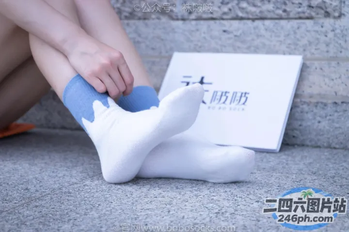 有人坐在地上，双脚抬起，手里拿着一本书