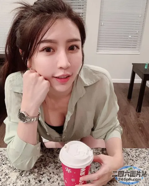 阿拉菲女人坐在桌子旁，手里拿着一杯咖啡