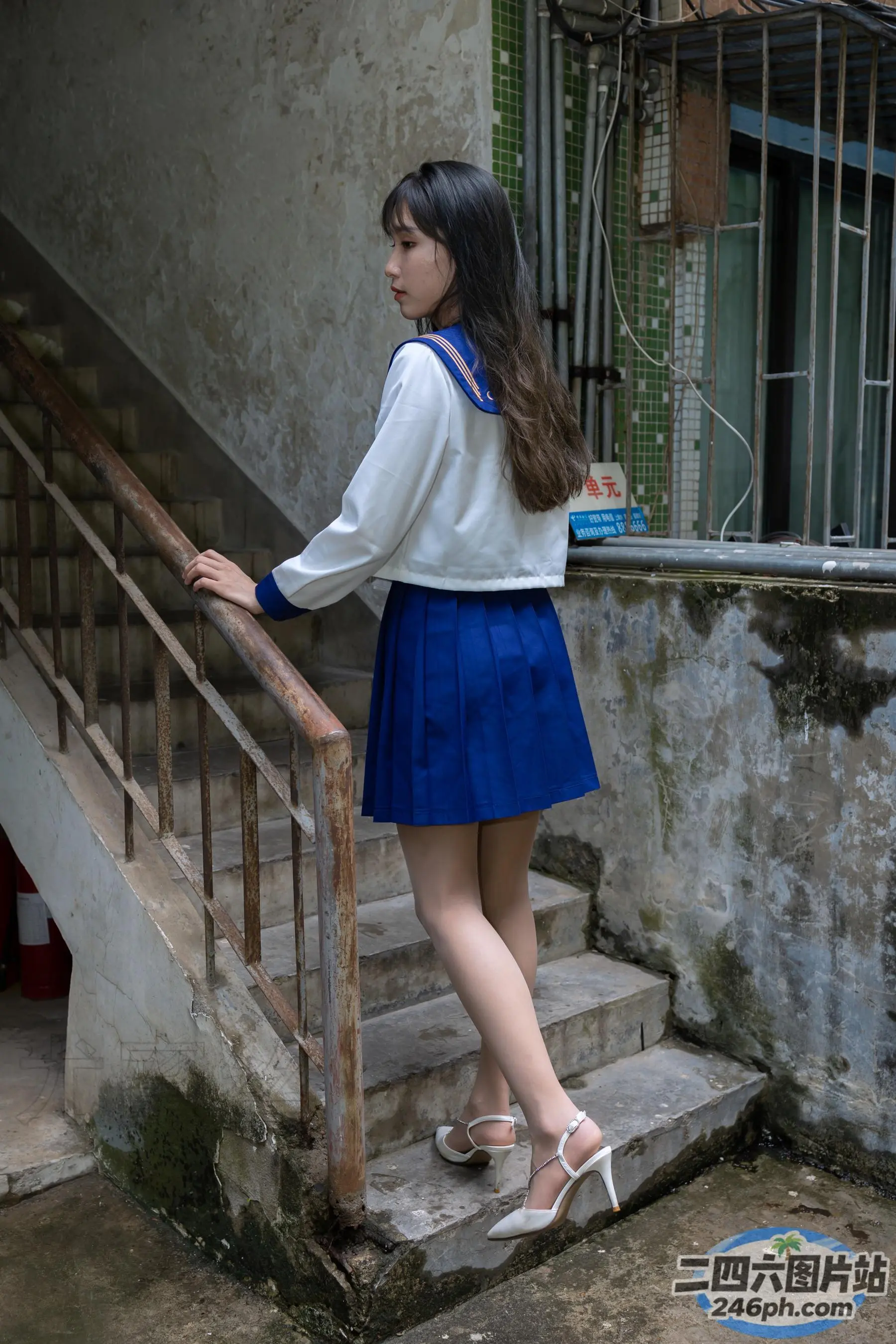身穿蓝色裙子和白色衬衫的亚洲女性站在楼梯上