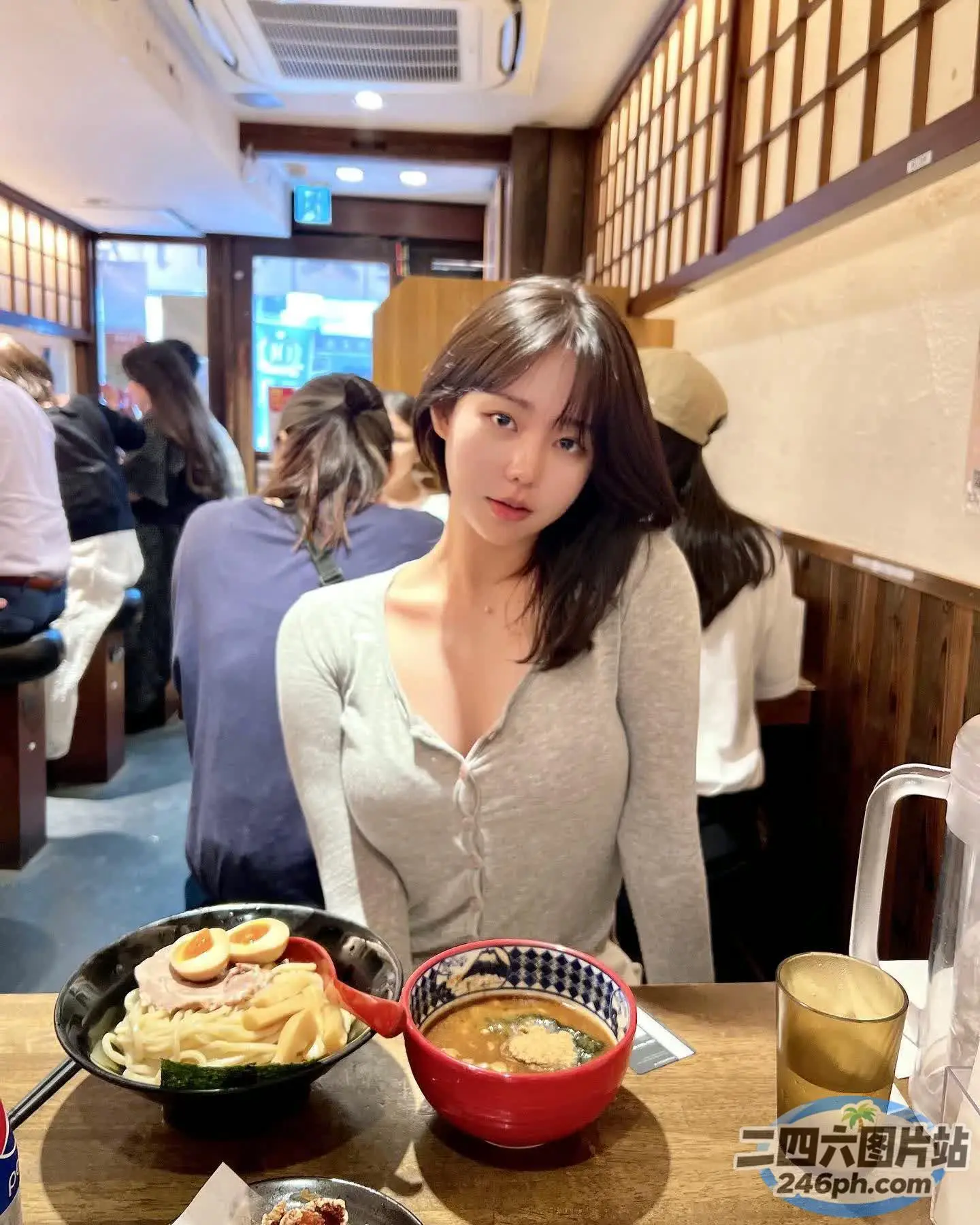 女人坐在桌子旁，手里拿着一碗食物和一碗汤