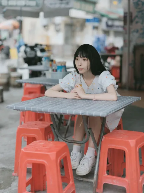 有一位女士坐在一张桌子旁，桌上坐着红色的凳子