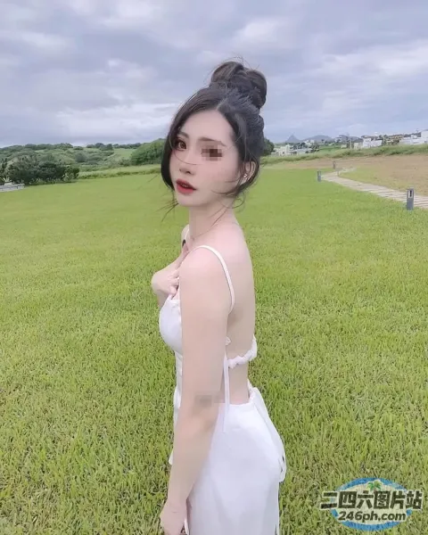 一个穿着白色连衣裙的女人站在田野里