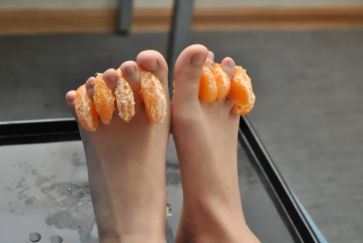 有人在吃一个去皮的橙子和吃了一半的橙子