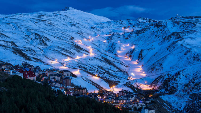 白雪皑皑的山上有滑雪场和夜晚灯火通明的小镇