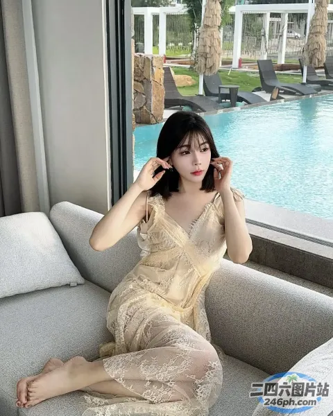 女人坐在房间的沙发上，背景是游泳池
