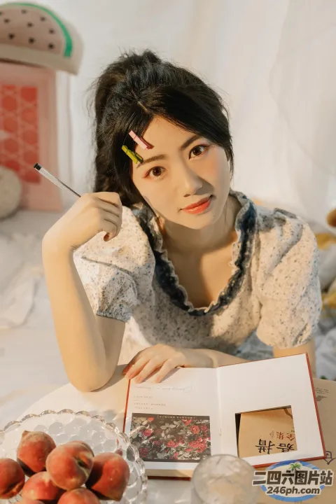 桌旁坐着一个女人，手里拿着一本书和一支笔