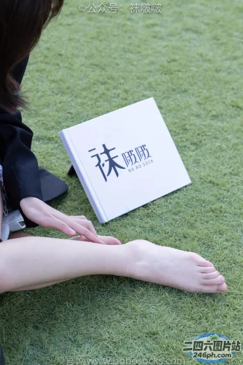 有个女人坐在草地上，手里拿着一本书