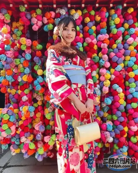 穿着和服的 araffe 女人站在一堵五颜六色的球墙前