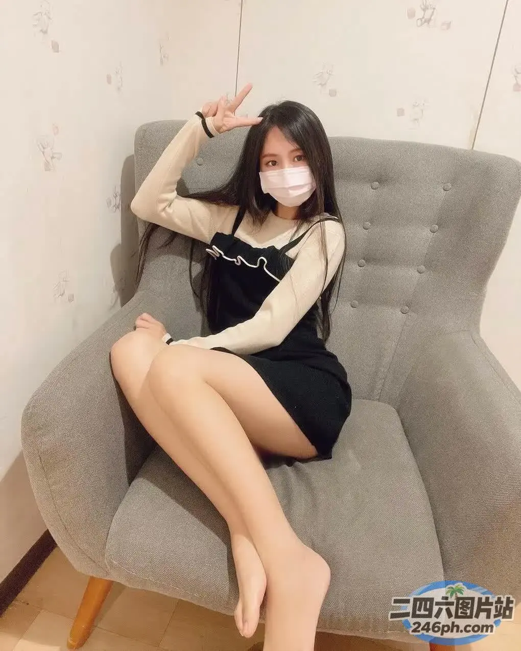 一名身穿黑色连衣裙的女子戴着口罩坐在椅子上