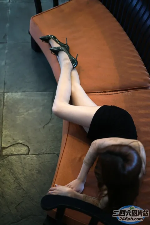 身穿黑色连衣裙的 araffe 女子双腿交叉躺在长凳上