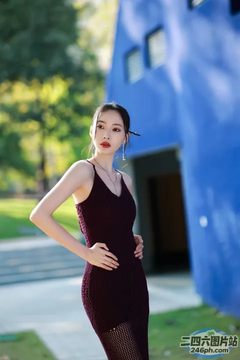 一名身穿黑色连衣裙的女子站在一栋蓝色建筑前