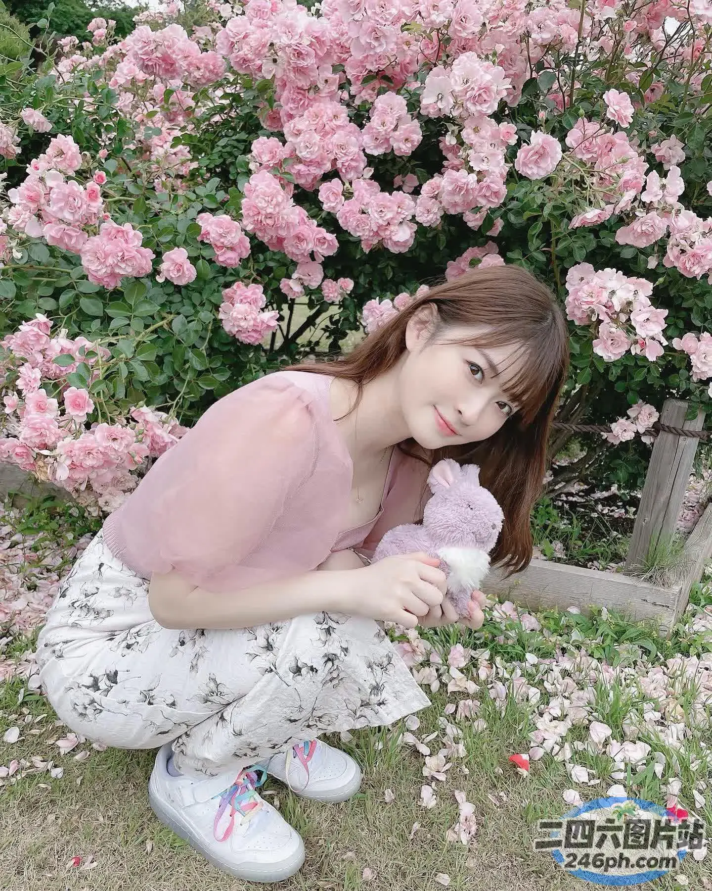 跪在一丛粉红色花朵前的 araffe 女孩
