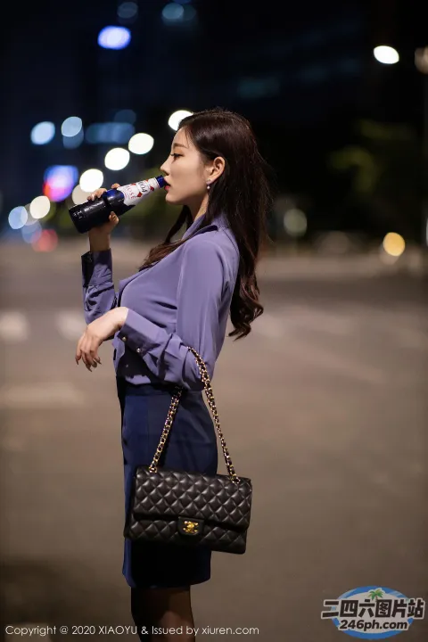 一个穿蓝色连衣裙的女人用瓶子喝水