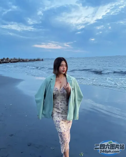肩上披着绿色夹克走在海滩上的女人