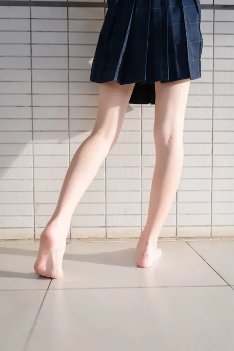 有一个穿着裙子的女人走在瓷砖地板上