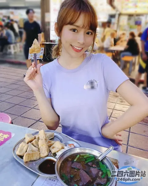 女人坐在一张桌子旁，手里拿着一盘食物和一杯饮料