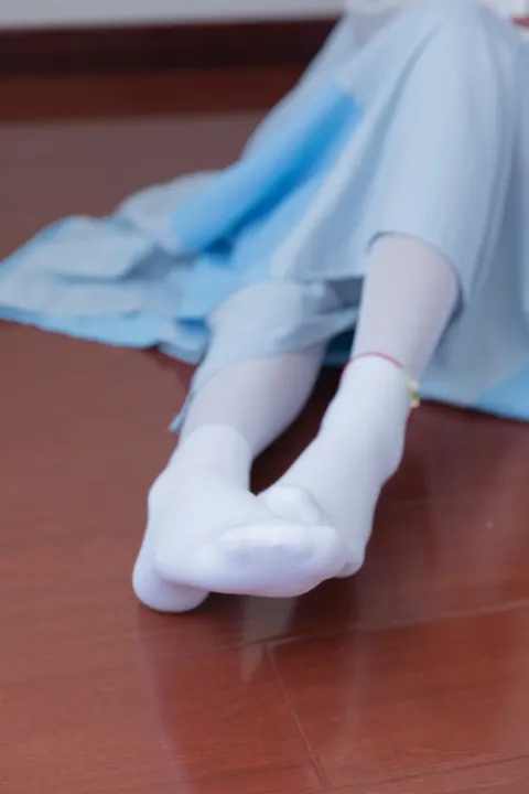 有一个女人坐在地板上，双脚抬起