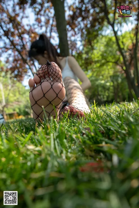 穿着白色连衣裙的阿拉伯人坐在草地上，脚上有网