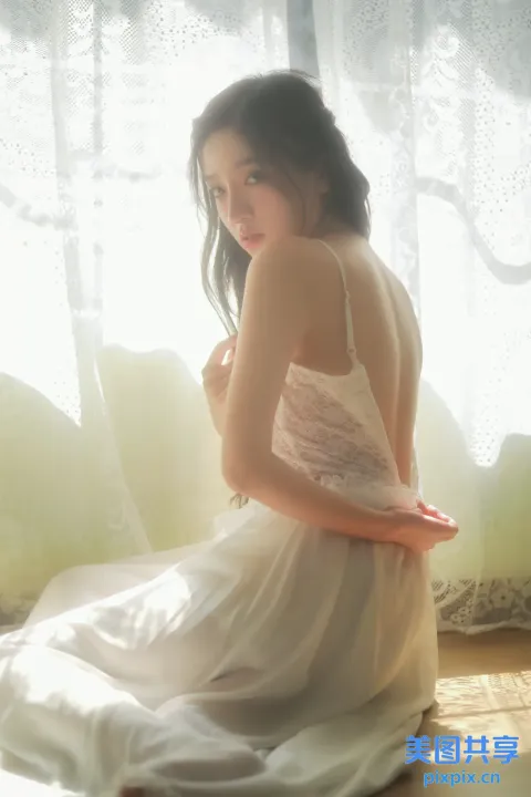 地板上坐着一个穿着白色连衣裙的女人