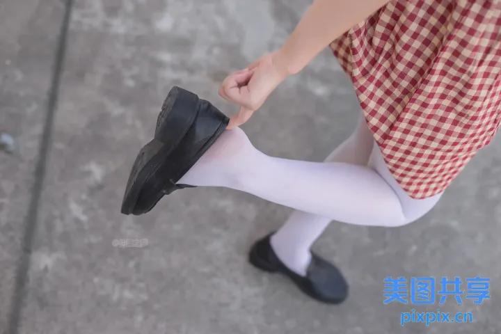 穿着裙子和鞋子的人拿着鞋子的 Araffed 视图