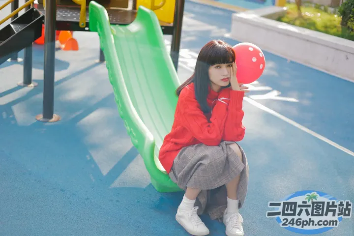 有一个女孩坐在滑梯上，手里拿着气球