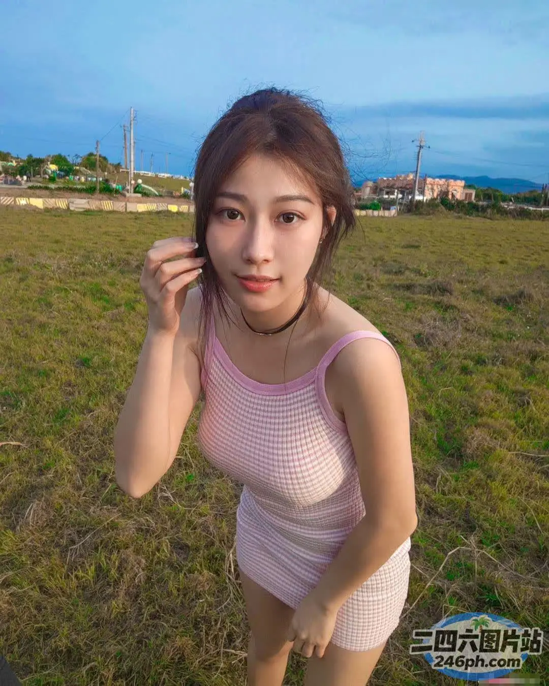 一个穿着粉红色连衣裙的女人站在田野里的特写