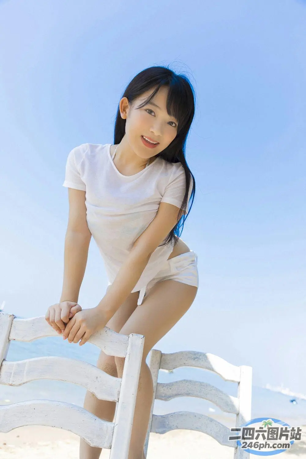 一个女人靠在海滩上的栅栏上的特写