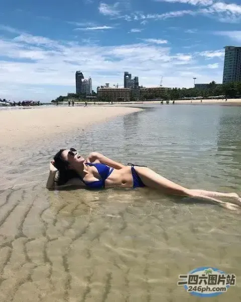 穿着蓝色比基尼躺在海滩上的阿拉伯裔女子
