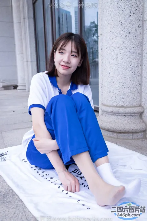 穿着蓝色连衣裙坐在人行道上的毯子上的 arafed 女人