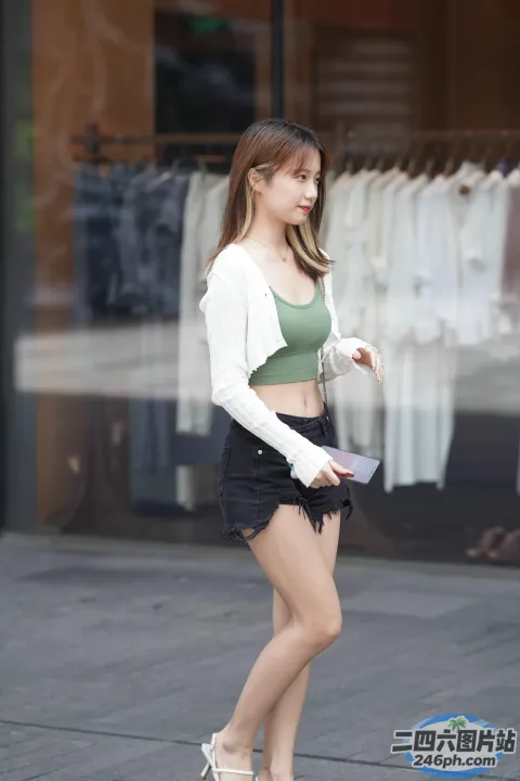 穿着绿色上衣和黑色短裤的 araffe 女孩走在街上