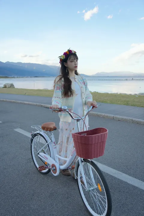 穿着白色连衣裙的 arafed 女人骑着白色自行车