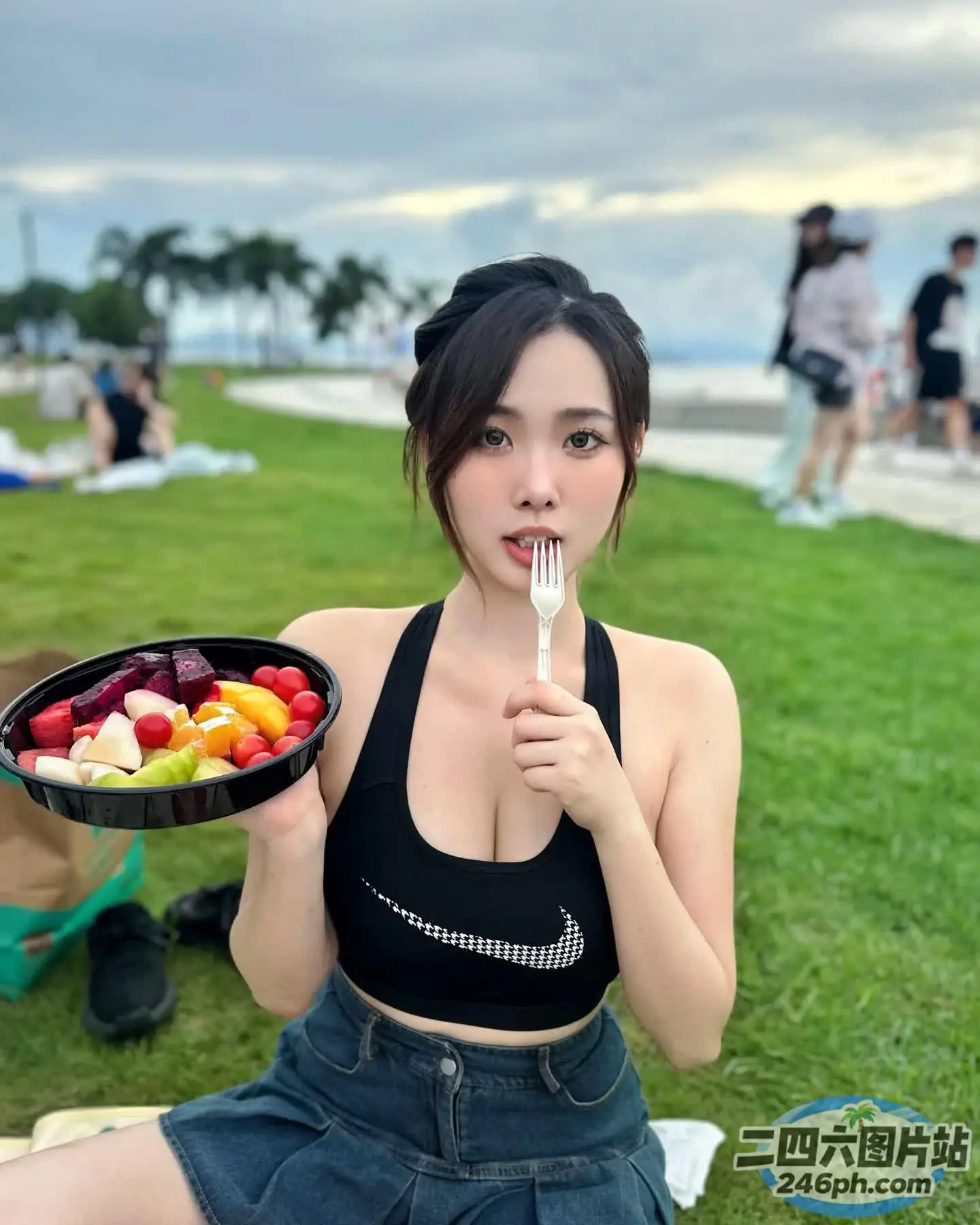 阿拉菲女人坐在毯子上，手里拿着一碗水果