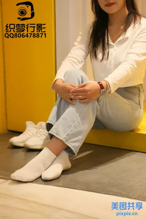 穿着白衬衫和牛仔裤坐在长凳上的 arafed 女人