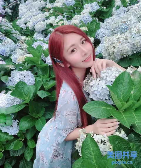 红发女子在花丛前摆姿势