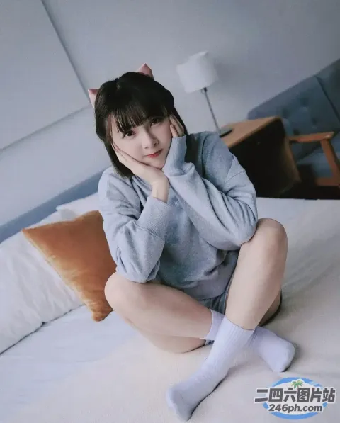阿拉菲坐在床上，手里拿着猫头带和一双袜子