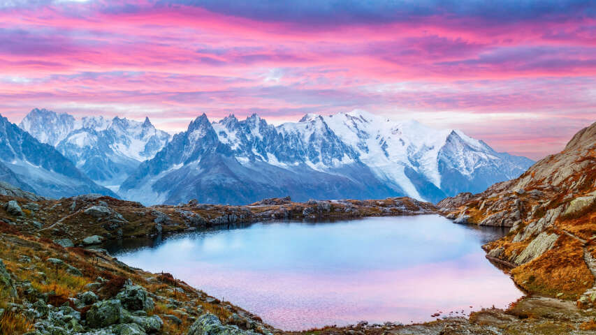 前景为湖泊，背景为粉红色天空的山脉