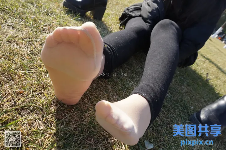 有人坐在草地上，双脚抬起